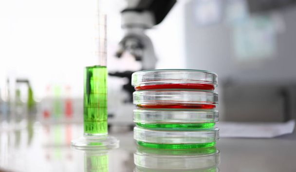 Κοντινό πλάνο εργαστηριακών γυάλινων δοχείων και φιάλης με χρωματιστό υγρό. Έρευνα της βιοτεχνολογίας και της φαρμακευτικής βιομηχανίας για τον άνθρωπο. Έννοια χημικών πειραμάτων - Φωτογραφία, εικόνα