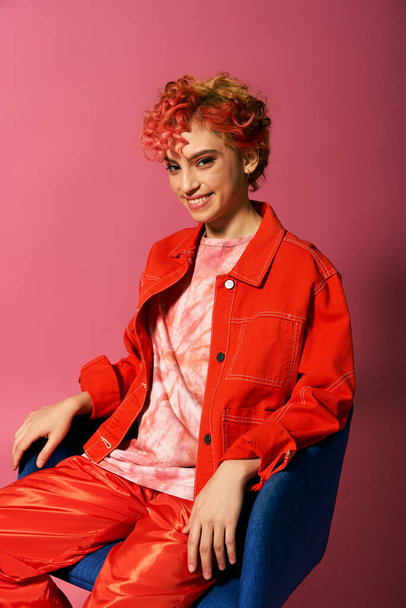 Μια νεαρή γυναίκα με κόκκινα μαλλιά κάθεται σε μια μπλε καρέκλα. - Φωτογραφία, εικόνα