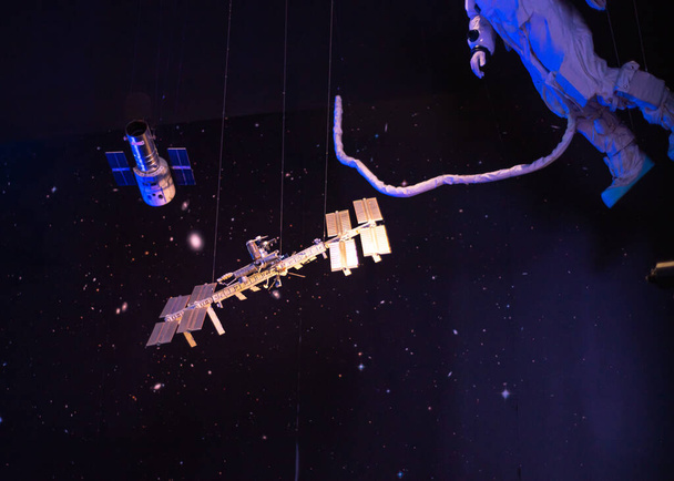 Model astronauty z bezpiecznym pasem pępowinowym Spacer kosmiczny po Międzynarodowej Stacji Kosmicznej, zintegrowana struktura kratownicy, orbita Ziemi i galaktyki wiszące na suficie muzeum w Teksasie. Stany Zjednoczone - Zdjęcie, obraz