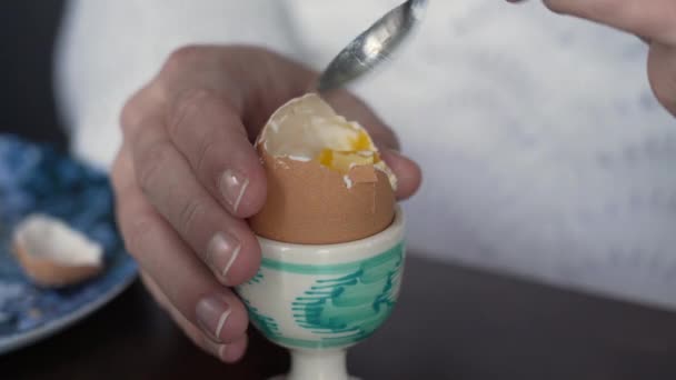 Close-up mão comendo ovo macio-cozido com parte superior rachada. Alimentos ricos em proteínas para o café da manhã - Filmagem, Vídeo