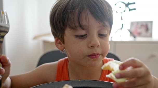 Маленький мальчик наслаждается салатом, кладя салат в рот руками - Кадры, видео