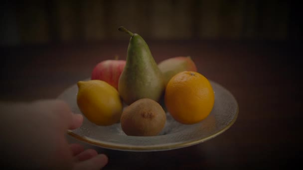 Osoba drží talíř s přírodními potravinami, ukazuje různé čerstvé ovoce. Stolní nádobí zvyšuje barevné zobrazení této základní složky potravin - Záběry, video