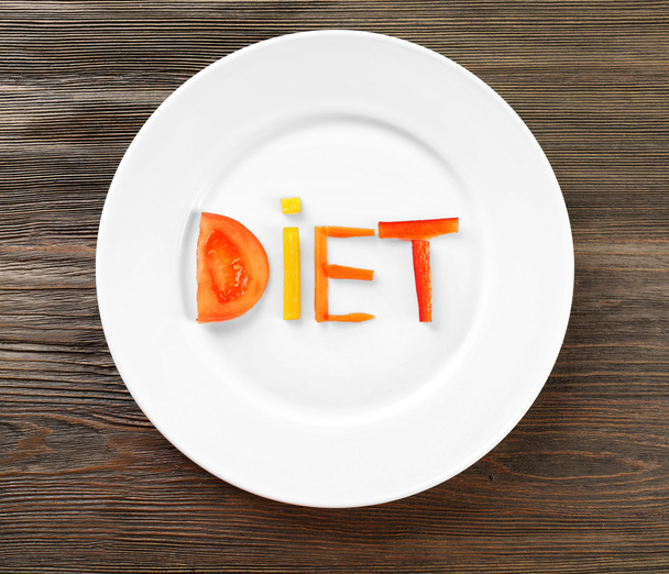 Word DIET made of sliced vegetables in white plate on wooden table, top view - Fotoğraf, Görsel