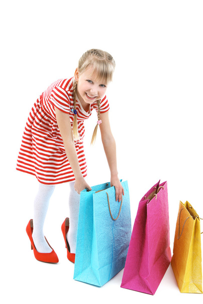 Beautiful little girl in mommy's  shoes with shopping bags isolated on white - Fotografie, Obrázek