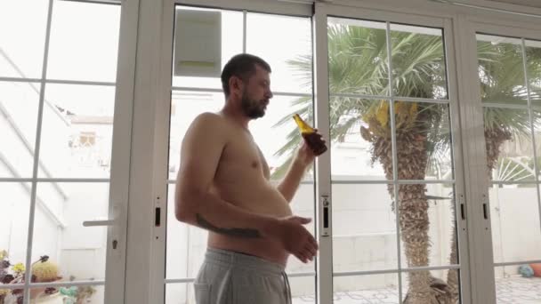 mężczyzna pijący piwo w domu - Materiał filmowy, wideo