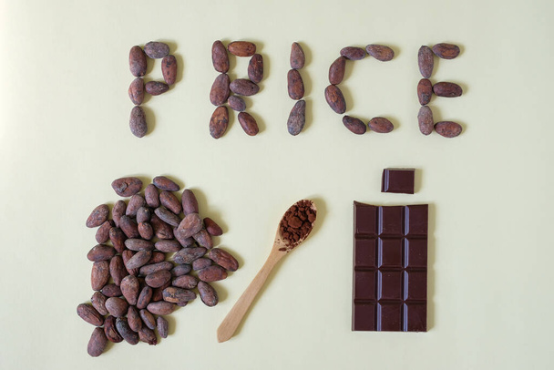 Słowo Price jest zrobione z ziaren kakaowych. Łyżka kakao. Batonik czekoladowy. Rosnące ceny produkcji czekolady. - Zdjęcie, obraz