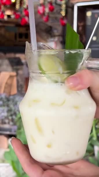 Высокий угол чаши с натуральным йогуртом и свежими фруктами лайм и пальмовый лист рядом с тарелками со свежими фруктами при дневном свете - Кадры, видео