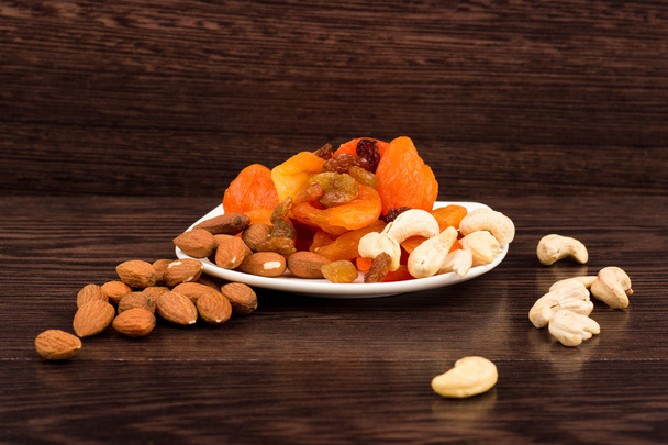 Snacks of nuts and dried fruits on a wooden surface - Photo, Image