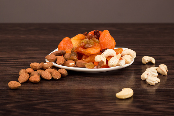Snacks van noten en gedroogde vruchten op een houten oppervlak - Foto, afbeelding