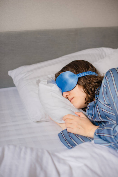 máscara para dormir de seda para dormir cómodamente. mujer está durmiendo en la cama en el hotel - Foto, imagen