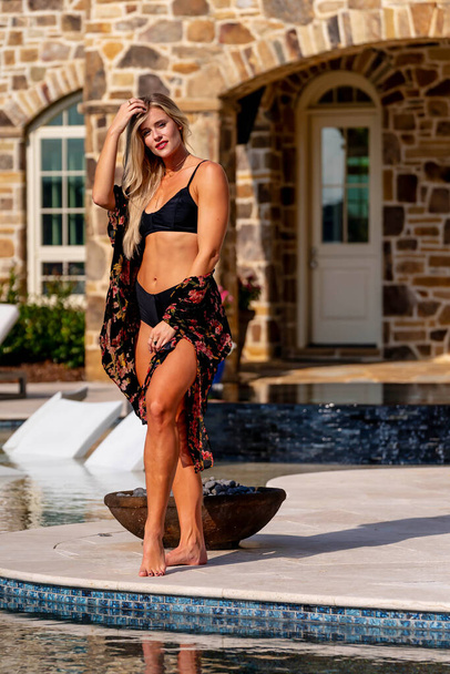 A gorgeous blonde bikini model enjoys a summers day by the pool - Фото, зображення