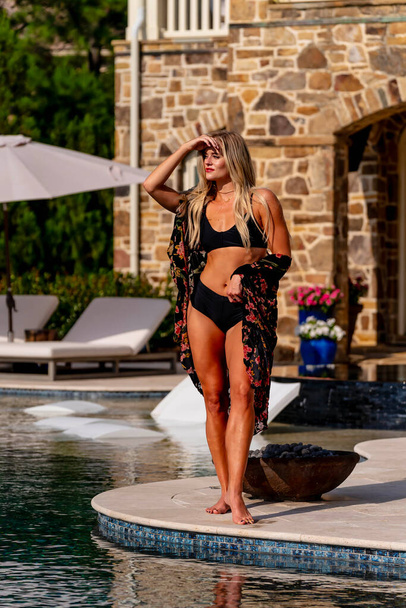 A gorgeous blonde bikini model enjoys a summers day by the pool - Фото, зображення