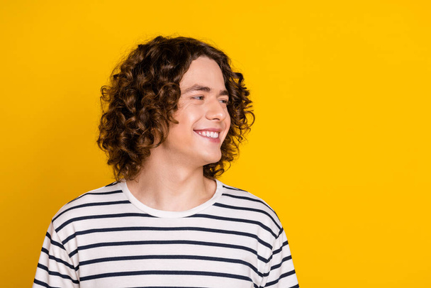 Portrait of attractive brunet curls teenage guy looking empty space smiling good emotions memories isolated on yellow color background. - Zdjęcie, obraz