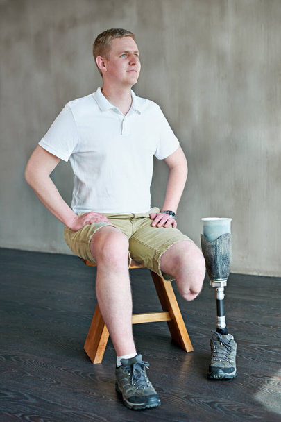 Man, amputee and thinking with prosthetic leg in gym, sitting with vision. Idea, physiotherapy and fitness for wellness for male person with disability, exercise and rehabilitation for mobility. - Фото, зображення