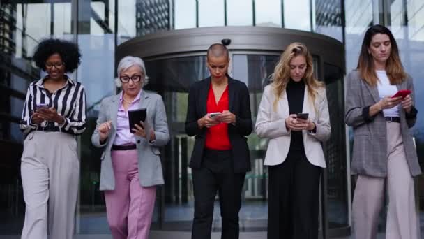 Çeşitli yaş grupları ve iş kadınları resmi olarak cep telefonu kullanarak yürüyorlar. Teknoloji, ofis binasının dışında ellerinde hücrelerle ciddi anlamda yetişkin kadınlara bağımlı hale geldi. - Video, Çekim