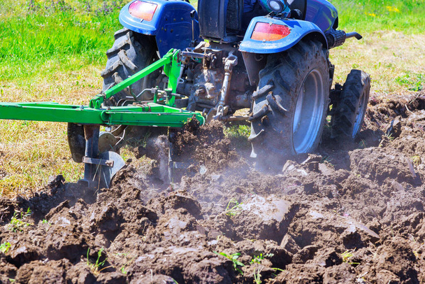 Tractor plows is preparing field, cultivates soil for sowing grain in spring time - Photo, Image