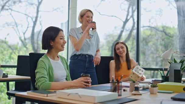 Zrelaksowani współpracownicy rozmawiają przyjaźnie na przerwie kawowej w sali konferencyjnej. Szczęśliwi koledzy śmiejący się ze wspólnego picia napoju w biurze. Młodzież lubi komunikację  - Zdjęcie, obraz