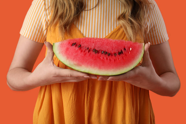 Hermosa joven con rodaja de melón fresco sobre fondo naranja - Foto, imagen