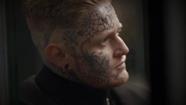 Intimidante hombre rebelde Maverick con tatuajes en la cabeza y la cara en estilo provocador - Imágenes, Vídeo