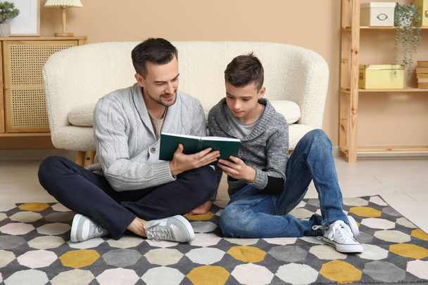 Padre y su pequeño hijo leyendo el libro en el suelo en casa - Foto, imagen