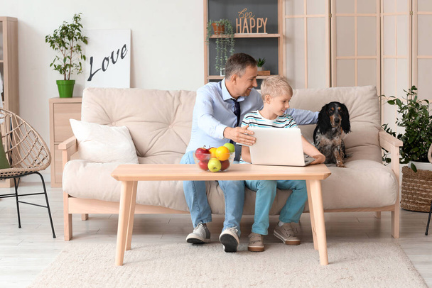 Dojrzałe lekarz z jego mały syn i pies za pomocą laptopa w domu - Zdjęcie, obraz