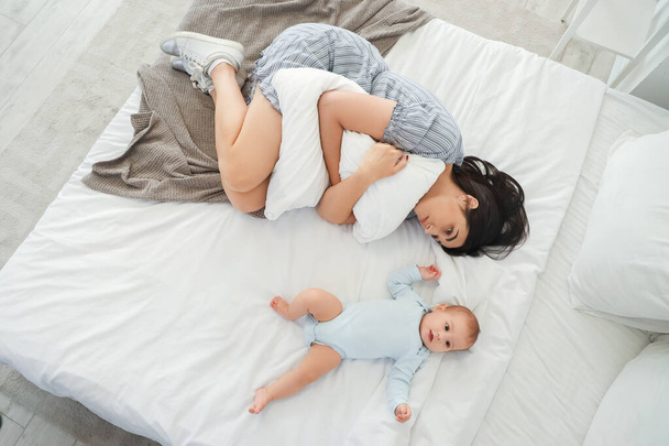Fiatal nő a baba szenved posztnatális depresszió az ágyban, felső nézet - Fotó, kép