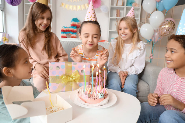 Χαριτωμένο κοριτσάκι με τους φίλους της κάνουν ευχή στο πάρτι γενεθλίων - Φωτογραφία, εικόνα