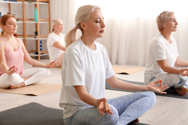 Зріла жінка медитує з групою в спортзалі - Фото, зображення