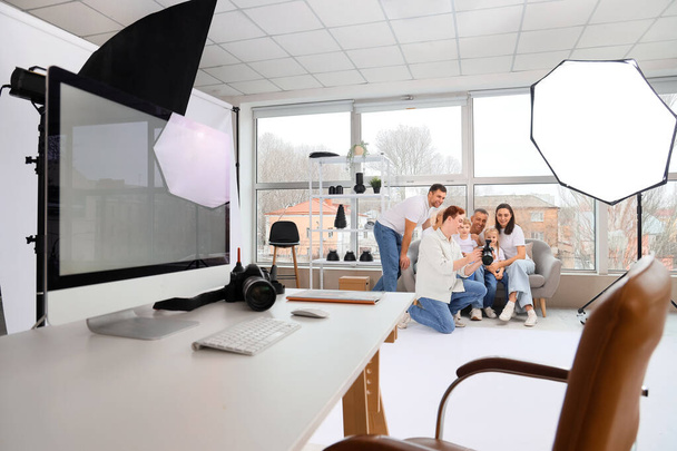 Männlicher Fotograf zeigt Fotos großer Familie im Studio - Foto, Bild