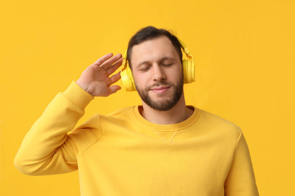 黄色の背景に現代のヘッドフォンの若い男 - 写真・画像