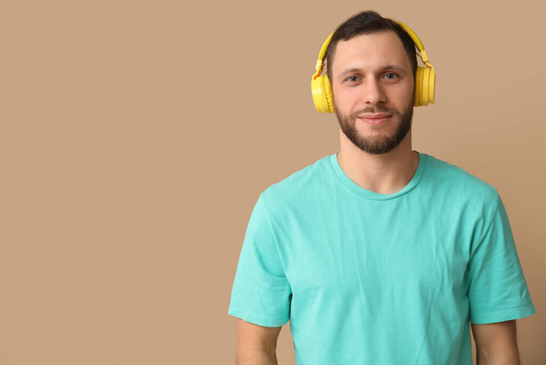 Fiatal férfi modern fejhallgató barna háttér - Fotó, kép