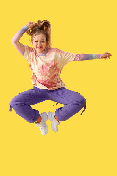 Hermosa joven feliz mujer bailando hip-hop sobre fondo amarillo - Foto, imagen