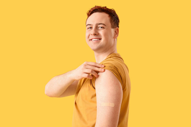 Nuori mies, jolla on laastari keltaisella pohjalla. Rokotuskäsite - Valokuva, kuva