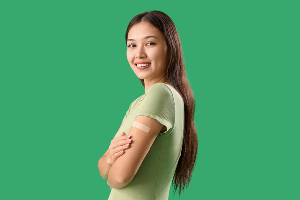 Beautiful young woman with applied medical patch on green background - Photo, Image