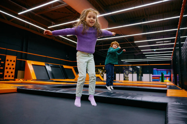 Des enfants heureux sautent sur une aire de jeux intérieure à la garderie ou à la garderie pour enfants. Concept d'enfance et de développement - Photo, image