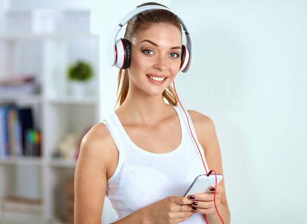 Woman with headphone listening music standing at home - Foto, Bild