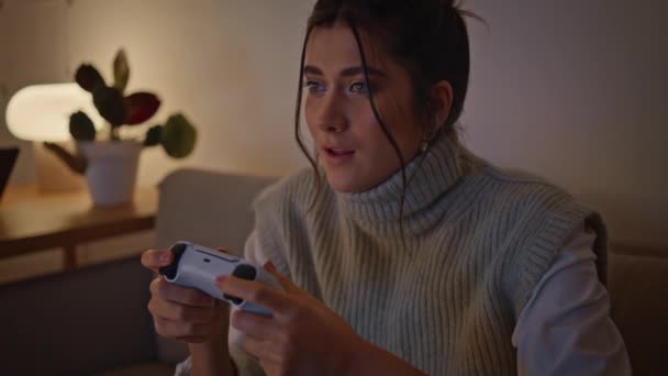 Komoly lány használja gamepad számítógépes játék esti ház közelkép. Női játékos nyomja gombok joystick érzés részt. Boldog nő játékos élvezi a versenyt éjjel otthon belső egyedül - Felvétel, videó