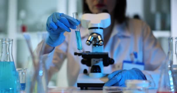 A tudós egy kék folyadékot tart és vizsgál meg egy kémcsőben laboratóriumi körülmények között. A mosó- és tisztítószerek minőségellenőrzése - Felvétel, videó