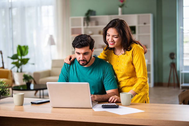 Boldog fiatal indiai házaspár ül az asztalra kiszámítása költségek használata egyszerű online banki szolgáltatás otthon - Fotó, kép