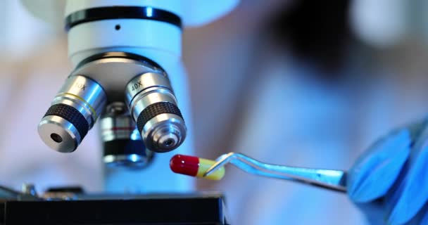 Microscopische analyse van rode en groene tabletten en microscoop. Farmaceutisch laboratoriumonderzoek - Video