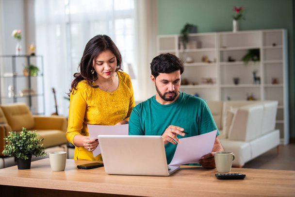 Щаслива молода індійська подружня пара сидить на столі Розрахувати витрати скористайтеся простим онлайн-банкінгом вдома - Фото, зображення