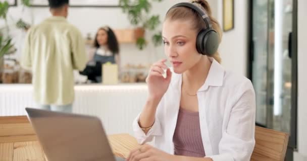 Ακουστικά, laptop και γυναίκα σε εικονική συνάντηση σε καφετέρια για online webinar. Τεχνολογία, επικοινωνία και γυναικεία δημιουργική freelancer σε βιντεοκλήση με υπολογιστή σε cafe ή εστιατόριο - Πλάνα, βίντεο