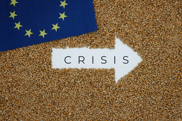 Tarwe. Rechterpijl. Het woord Crisis. Korrelachtergrond. vlag van de Europese Unie. Graancrisis. - Foto, afbeelding
