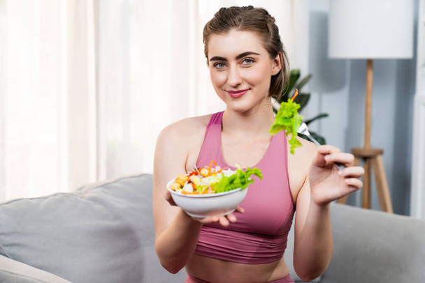 Gesunde, sportliche und vegetarische Frau in Sportbekleidung mit einer Schüssel Obst und Gemüse. Gesunde Küchennahrung und veganer Lebensstil für Fitness-Körperbau bei Frohsinn-Home-Konzept. - Foto, Bild