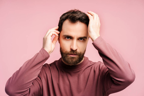 Portrait of worried man loss hair looking at mirror isolated on pink background. Treatment, alopecia problem and hair care concept - Photo, Image