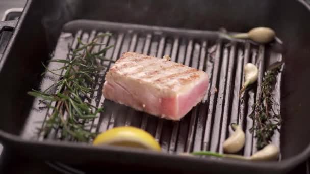 pedaço de atum com limão, alho e alecrim frito em óleo em uma frigideira. Espaço de cópia - Filmagem, Vídeo