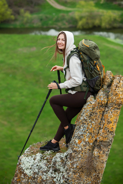 Sırt çantalı genç bir kadın dağda yürüyüş yapıyor. Yürüyüş konsepti. Uçurumları geziyorum. Seyahat, gezgin.. - Fotoğraf, Görsel