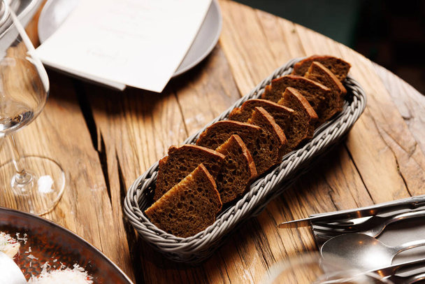 新鮮にスライスした茶色のパンのバスケットは木製のテーブルの上にあります - 写真・画像