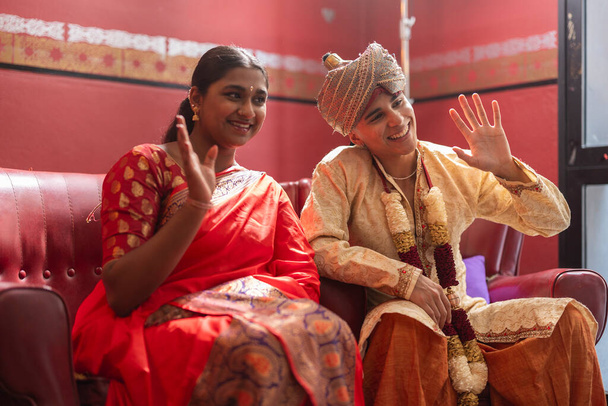 Junge Menschen in traditioneller indischer Kleidung teilen einen spielerischen Gruß und strahlen kulturelle Freude aus. - Foto, Bild