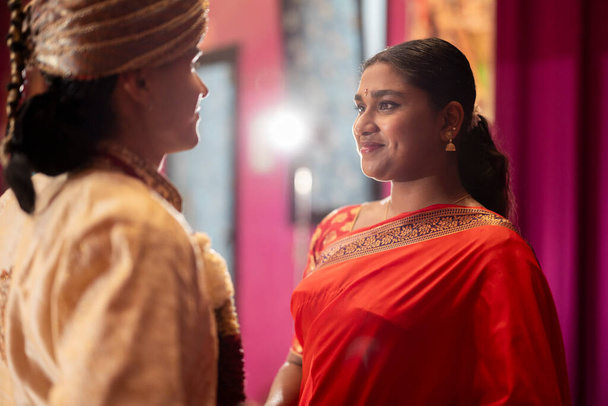 Два молодых индийца делятся личным обменом, одетые в яркие традиционные одежды. - Фото, изображение